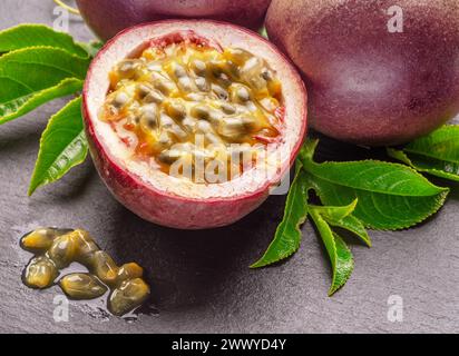 Frutti della passione viola scuro e metà del frutto della maracuya isolati su sfondo grigio grafite ardesia. Foto Stock
