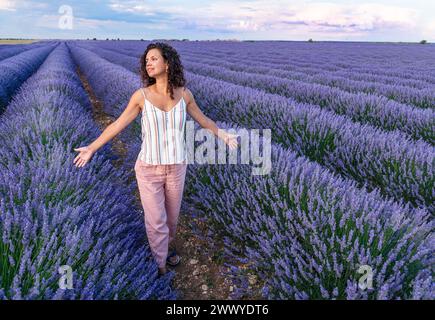 Donna che cammina nel campo di lavanda. Cielo nuvoloso sullo sfondo. Brihuega, Spagna. Foto Stock