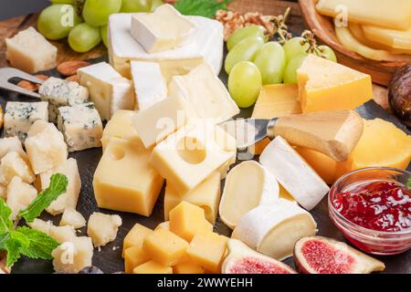 Varietà di formaggi a fette con frutta, menta, noci e taglierini. Un meraviglioso sfondo di formaggi per i vostri progetti. Foto Stock