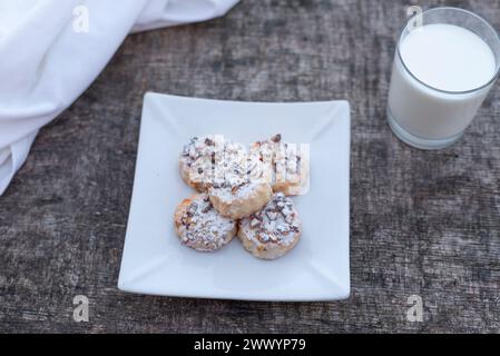 Biscotti appena sfornati sul piatto con un bicchiere di latte su un tavolo di legno. Foto Stock