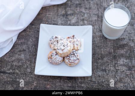 Biscotti appena sfornati sul piatto con un bicchiere di latte su un tavolo di legno. Foto Stock