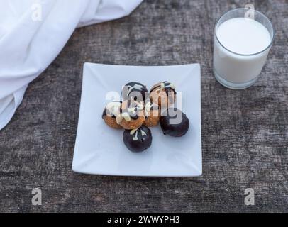 Biscotti appena sfornati sul piatto con un bicchiere di latte su un tavolo di legno. Foto Stock