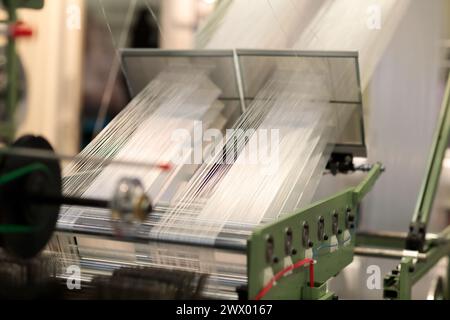 Macchina industriale per la produzione di tessiture. Concetto industriale di produzione tessile e tessile. Messa a fuoco selettiva. Foto Stock