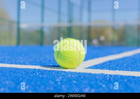 una palla in un campo da paddle tennis blu, racchetta sportiva Foto Stock