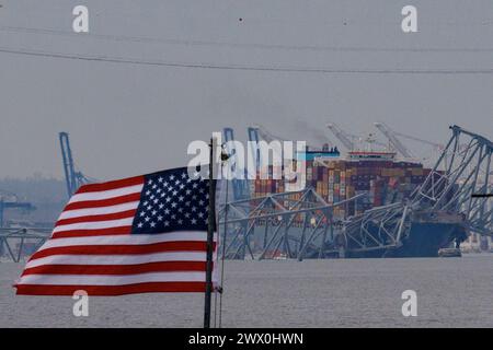 Baltimora, Stati Uniti d'America. 26 marzo 2024. Una bandiera americana viene vista insieme ai resti di Francis Scott Key Bridge fuori Baltimora, Maryland, dopo che una nave portacontainer ha perso energia elettrica e ha colpito il ponte nelle prime ore del mattino di martedì 26 marzo 2024. Credito: Aaron Schwartz/CNP/Sipa USA credito: SIPA USA/Alamy Live News Foto Stock