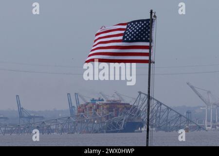 Baltimora, Stati Uniti d'America. 26 marzo 2024. Una bandiera americana viene vista insieme ai resti di Francis Scott Key Bridge fuori Baltimora, Maryland, dopo che una nave portacontainer ha perso energia elettrica e ha colpito il ponte nelle prime ore del mattino di martedì 26 marzo 2024. Credito: Aaron Schwartz/CNP/Sipa USA credito: SIPA USA/Alamy Live News Foto Stock