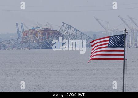 Baltimora, Stati Uniti d'America. 26 marzo 2024. Una bandiera americana viene vista insieme ai resti di Francis Scott Key Bridge fuori Baltimora, Maryland, dopo che una nave portacontainer ha perso energia elettrica e ha colpito il ponte nelle prime ore del mattino di martedì 26 marzo 2024. Credito: Aaron Schwartz/CNP/Sipa USA credito: SIPA USA/Alamy Live News Foto Stock