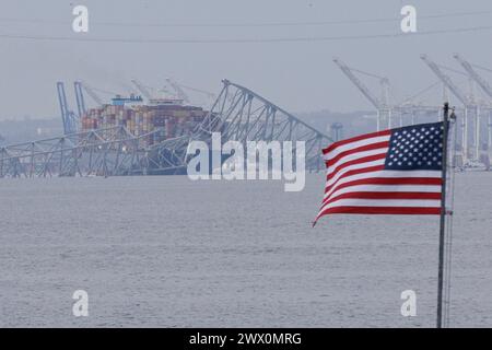 Una bandiera americana viene vista insieme ai resti di Francis Scott Key Bridge fuori Baltimora, Maryland, dopo che una nave portacontainer ha perso energia elettrica e ha colpito il ponte nelle prime ore del mattino di martedì 26 marzo 2024. Credito: Aaron Schwartz/CNP Foto Stock