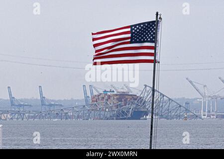 Una bandiera americana viene vista insieme ai resti di Francis Scott Key Bridge fuori Baltimora, Maryland, dopo che una nave portacontainer ha perso energia elettrica e ha colpito il ponte nelle prime ore del mattino di martedì 26 marzo 2024. Credito: Aaron Schwartz/CNP Foto Stock