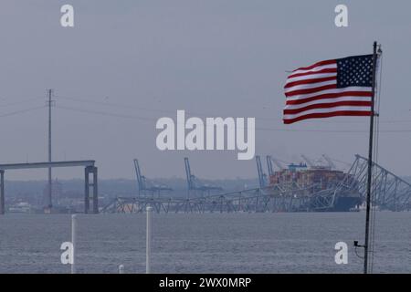 Una bandiera americana viene vista insieme ai resti di Francis Scott Key Bridge fuori Baltimora, Maryland, dopo che una nave portacontainer ha perso energia elettrica e ha colpito il ponte nelle prime ore del mattino di martedì 26 marzo 2024. Credito: Aaron Schwartz/CNP Foto Stock