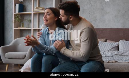 Caucasian man apologizing husband calming anxious annoyed wife ask forgiveness after family conflict crying tears woman emotional complain listen to Stock Photo