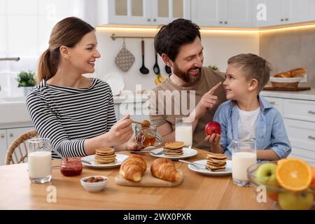 Famiglia felice che si diverte durante la colazione al tavolo in cucina Foto Stock