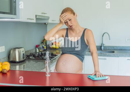 Una donna incinta stanca siede in cucina dopo la pulizia. Salute e vitalità di una donna incinta Foto Stock