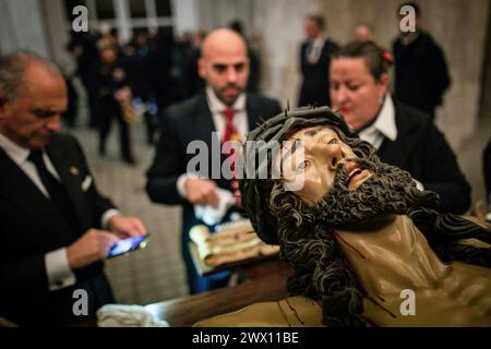 Madrid, Spagna. 26 marzo 2024. Un gruppo di fratelli pulisce e asciuga il volto del Santo Cristo della fede, popolarmente conosciuto come Cristo degli alberdieri dalla pioggia all'interno del Palazzo reale di Madrid. Questo martedì Santo, con la minaccia della pioggia e il rischio di sospensione a causa del maltempo, il Santísimo Cristo de la Fe, popolarmente noto come Cristo de los Alabarderos, ha trasformato la cattedrale militare di Madrid al Palazzo reale. Credito: SOPA Images Limited/Alamy Live News Foto Stock