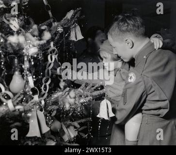 La fotografia scattata la vigilia di Natale in un ospedale americano di Londra mostra un soldato americano che tiene in braccio un bambino di quattro anni rimasto orfano da un blitz tedesco CA. 1944 Foto Stock