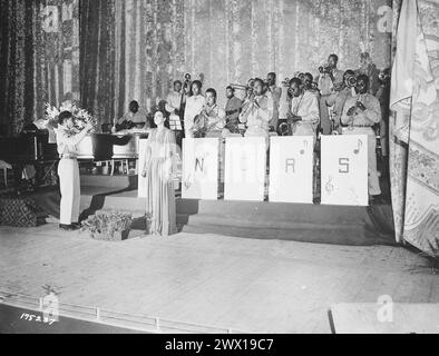 La signorina Josephine Baker, popolare interprete teatrale, canta l'inno nazionale come finale dello spettacolo tenuto al Teatro Municipale di Orano, Algeria, N. Africa. La band è diretta da T/Sgt. Frank W. Weiss CA. Maggio 1943 Foto Stock