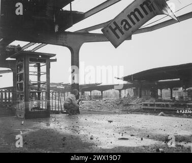 Allerta per il movimento nemico, un privato di prima classe accovacciato con una carabina alla stazione ferroviaria nella città appena catturata di Hamm, Germania ca. 6 aprile 1945 Foto Stock