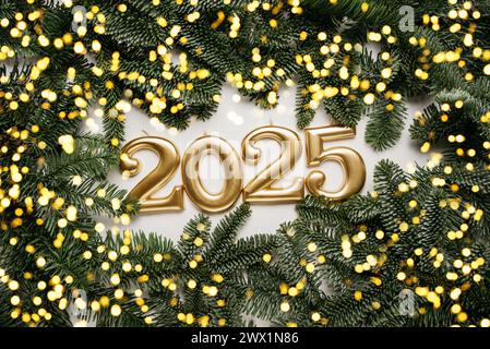 Sfondo festivo felice anno nuovo 2025. Numeri dell'anno 2025 realizzati con candele d'oro sullo sfondo con abete. Festeggiamo le vacanze di Capodanno, primo piano. Spazio per il testo Foto Stock