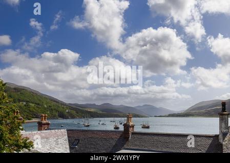 Sopra i tetti di Ullapool, una vista pittoresca si dispiega sulle barche ormeggiate sul lago, adagiate sulla grandiosità delle Highlands scozzesi Foto Stock