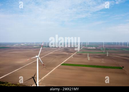 Le file su file di torreggianti turbine eoliche dominano il paesaggio, raccogliendo energia durante le pause del giorno Foto Stock