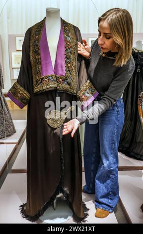 Leighton House, Londra, Regno Unito. 27 marzo 2024. Cappotto da sera di proprietà di Maud, c 1912 con bordo in stile ikat sovrapposto a nastro dorato. Una mostra di abiti rari e significativi a livello nazionale che mette in luce la storia intima di una madre della classe media e della sua figlia benestante in un momento storico che ha plasmato il modo in cui la moda viene consumata oggi.Paul Quezada-Neiman/Alamy Live News crediti: Paul Quezada-Neiman/Alamy Live News Foto Stock