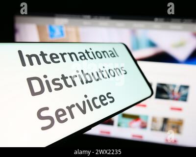 Smartphone con logo della società britannica International Distribuctions Services plc davanti al sito Web. Mettere a fuoco la parte centrale sinistra del display del telefono. Foto Stock