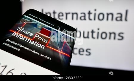 Telefono cellulare con sito web della società britannica International Distribuctions Services plc davanti al logo. Mettere a fuoco in alto a sinistra sul display del telefono. Foto Stock