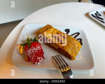 Strudel con mele e decorato con fragole e sciroppo al cioccolato Foto Stock