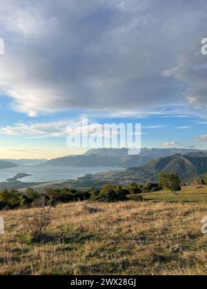 Prato verde sul mare circondato da una catena montuosa Foto Stock