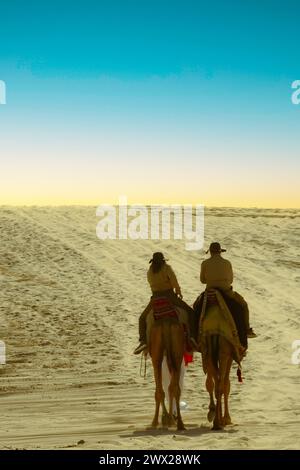 I turisti cavalcano i cammelli nel deserto del mare interno, Caravan che attraversa le dune di sabbia nel deserto del mare interno, Doha Qatar Foto Stock