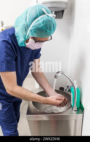 veterinario uomo chirurgo in abiti epi che si preparano a operare lavando le mani nel lavello della clinica Foto Stock