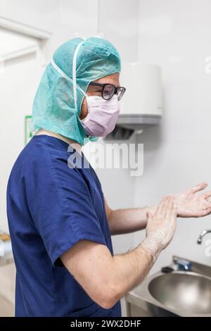veterinario uomo chirurgo in abiti epi che si preparano a operare lavando le mani nel lavello della clinica Foto Stock