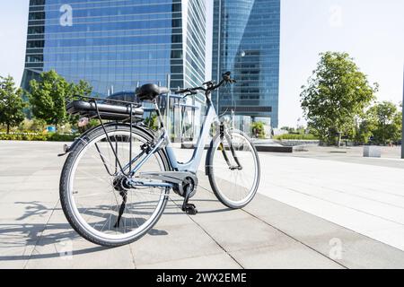 bicicletta elettrica di fronte alle torri dell'ufficio nella grande città Foto Stock