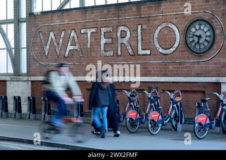 Segnale sbiadito per la stazione ferroviaria di Waterloo mentre le persone passano le biciclette il 6 marzo 2024 a Londra, Regno Unito. La stazione di Waterloo, nota anche come London Waterloo, è un importante capolinea centrale della rete ferroviaria nazionale nel borgo londinese di Lambeth. È collegato a una stazione della metropolitana di Londra con lo stesso nome. Waterloo è la terza stazione più trafficata del Regno Unito, con circa 60 milioni di passeggeri all'anno a partire dal 2023. Foto Stock