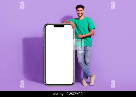 Foto a tutto corpo di un giovane promoter moderno sito Web per smartphone interfaccia minima con il dito diretto nuova app isolata su sfondo di colore viola Foto Stock
