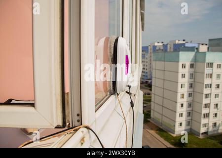 Un moderno robot aspirapolvere lavavetri lavavetri in un appartamento su un balcone. Vista dall'esterno dalla strada. Sicurezza dalle cadute dall'alto, automati Foto Stock