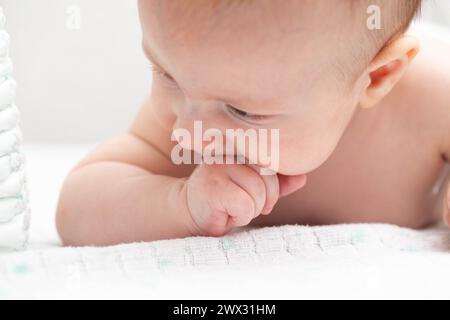 Un bambino di tre anni gli succhia i pugni in bocca. Il concetto del riflesso succhiante nei bambini. Foto Stock