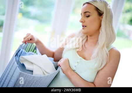 Donna incinta stanca che trasporta un cestello per il lavaggio Foto Stock