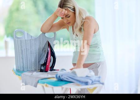 Donna incinta stanca di stirare Foto Stock