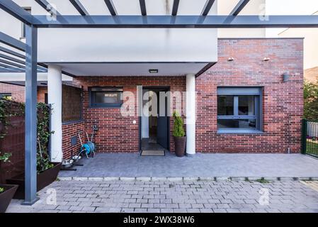 Portico e porta di accesso di una casa unifamiliare con piante e giardini sul perimetro Foto Stock