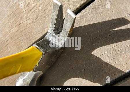 Chiodi dalla testa di un martello di metallo poggiati su alcune tavole di legno che gettano su di esse una grande ombra nera Foto Stock