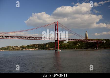 Il 25 aprile ponte e statua di Cristo sopra il fiume Tago nel quartiere Almada di Lisbona. Foto Stock