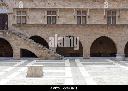 Parte del cortile interno del palazzo dei Cavalieri ospedalieri a Rodi, Grecia. Pavimentazione in pietra, scale e archi, nessuna persona visibile Foto Stock