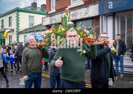 Quattro uomini trasportano una statua fiorita di San Patrizio durante la parata del giorno di San Patrizio del 2024 a Warrington Foto Stock