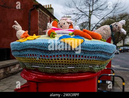 North Berwick, East Lothian, Scozia, Regno Unito, 27 marzo 2024. Decorazione del topper a tema pasquale a uncinetto su una cassetta postale rossa Royal mail durante il periodo di Pasqua. Crediti: Sally Anderson/Alamy Live News Foto Stock