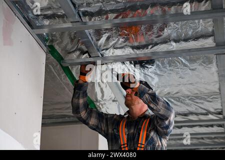 Costruzione di cartongesso a casa. installazione di un telaio metallico sul soffitto. Foto Stock