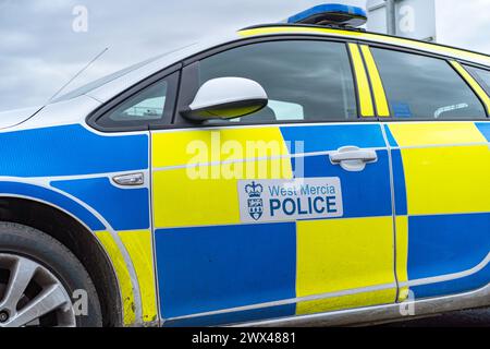 Angolo basso, vista laterale ravvicinata dell'auto della polizia di West Mercia (lato passeggero, lato marciapiede) parcheggiata isolata all'aperto senza persone. Veicolo per la risposta in caso di incidente. Foto Stock