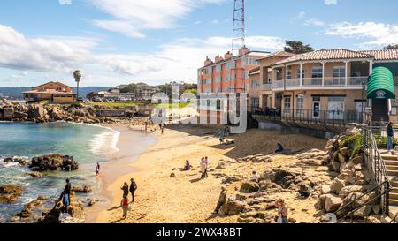 Macabee Beach o McAbee Beach vicino a Cannery Row a Monterey, California, Stati Uniti. Turisti in spiaggia con edifici storici sulla costa. Foto Stock