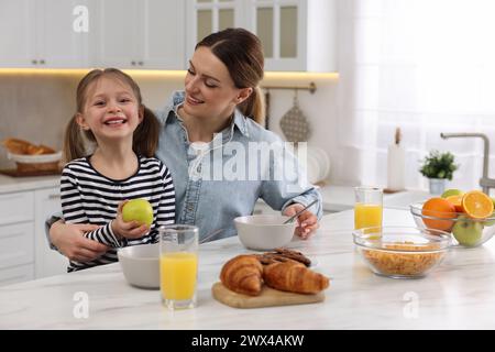 La madre e la sua piccola e carina fanno colazione a tavola in cucina Foto Stock