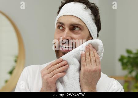 Lavare la faccia. Uomo con fascia e asciugamano in bagno Foto Stock